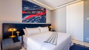 A hotel room with a large bed, two bedside tables, a headboard, and a wall-mounted artwork.