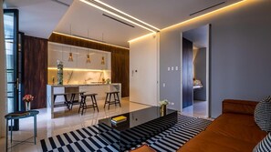 A modern kitchen with a central island, bar stools, pendant lighting, and a black and white striped rug.