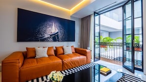 A modern living room with a leather sofa, a glass coffee table, and a large window with a view of a balcony.