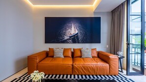 Un soggiorno moderno con un divano in pelle, un grande quadro astratto e una porta vetrata che dà su un balcone.