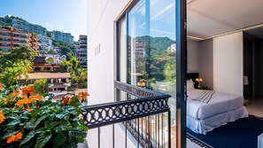 Ein Balkon mit Blick auf eine Stadtlandschaft und ein Bett mit weißer Matratze und schwarzem Kopfteil.