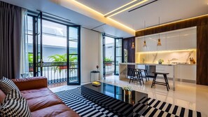 A modern living room with a sofa, a coffee table, and a kitchen area with a dining set.