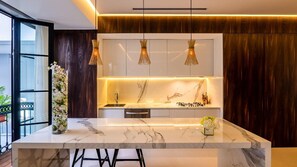 Une cuisine moderne dotée d’un plan de travail en marbre, de luminaires suspendus et d’une cuisinière intégrée.