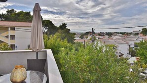 A balcony with a table, a chair, and a decorative vase. - Apartments Ruzica (Banjol)