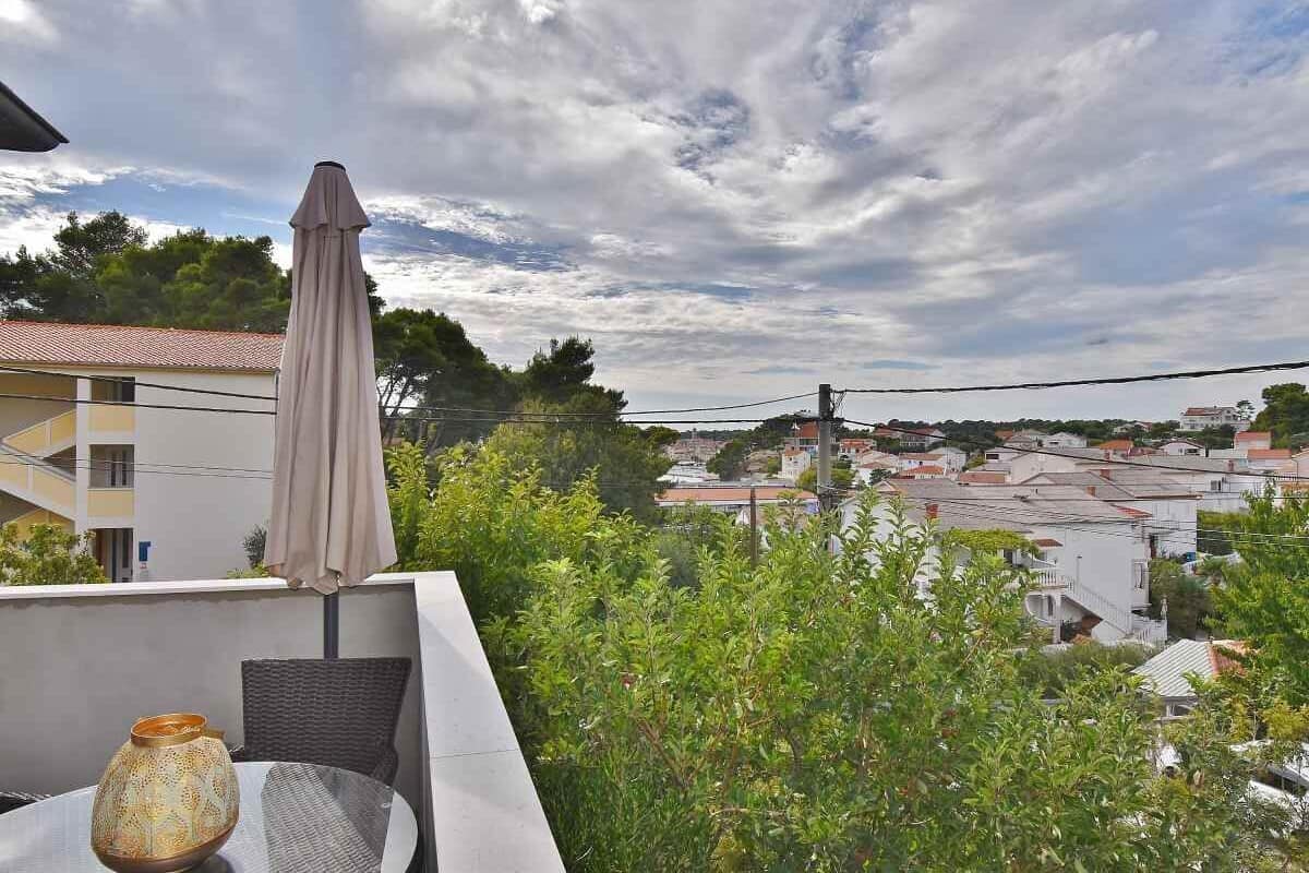 A balcony with a table, a chair, and a decorative vase.