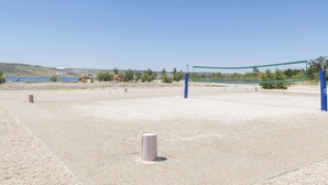 An outdoor volleyball court with a net, surrounded by a gravel surface and a clear blue sky. - House Paklenica Stone ll (Seline)