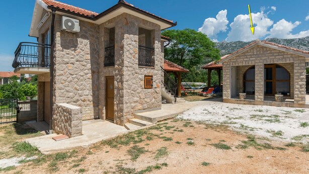 A stone building with a balcony, a small attached structure, and a clear sky. - House Paklenica Stone ll (Seline)