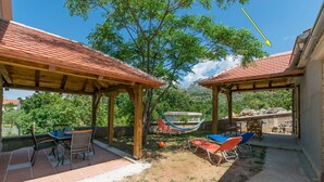 An outdoor patio with wooden pergolas, a table with chairs, and a hammock. - House Paklenica Stone ll (Seline)