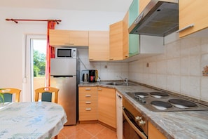 A compact kitchen with a microwave, coffee maker, and stove. - Apartments and Room Ljubica (Lopar)