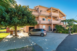 A multi-story residential building with a car parked in the driveway.