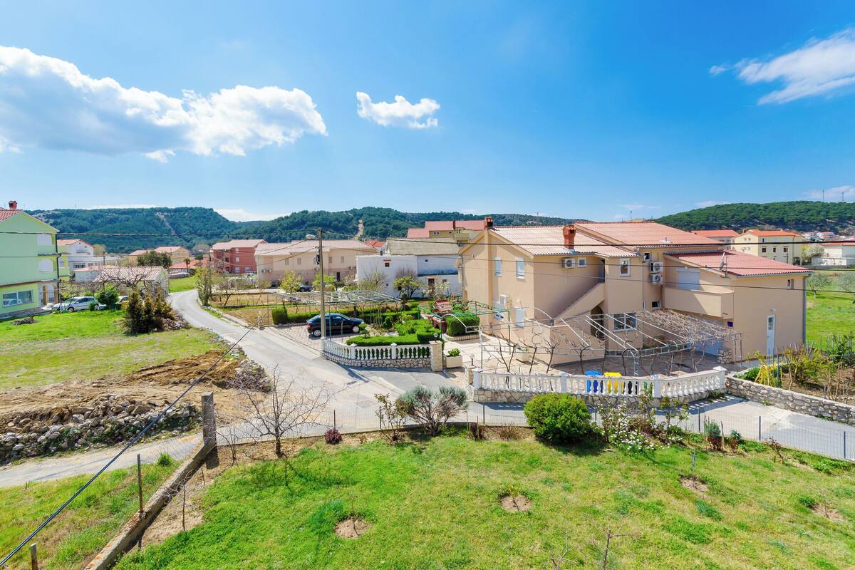 Un quartiere residenziale con case, una strada e una collina verde sullo sfondo.