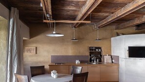 Une cuisine rustique avec des poutres en bois, une table à manger ronde et des luminaires suspendus.