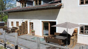 Un chalet doté d’une terrasse en bois, d’un espace salon extérieur et d’une grande porte-fenêtre coulissante.