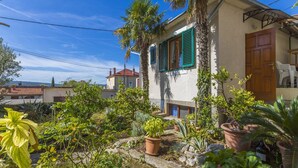 A house with a garden, a wooden door, and a window with green shutters. - House Haus Vlady (Crikvenica)