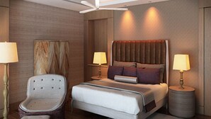 Una habitación de hotel moderna con una cama grande, una silla, dos lámparas de noche y un ventilador de techo.