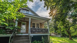 Ein zweigeschossiges Haus mit Veranda, überdachter Treppe und gepflegtem Rasen.
