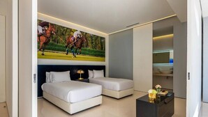 Una camera da letto moderna con due letti, un comodino, un tavolino da caffè e una TV a parete che mostra una partita di polo.