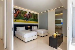 Ein modernes Schlafzimmer mit zwei Betten, einem Nachttisch, einem Couchtisch und einem an der Wand befestigten Fernseher, der ein Polospiel zeigt.