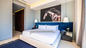 Ein modernes Hotelzimmer mit einem großen Bett, einem Kopfteil mit einem Pferdebild, Nachttischlampen und einem Nachttisch.