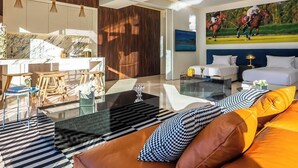 Una sala de estar moderna con una mesa de centro de vidrio, un sofá con cojines estampados y una zona de comedor con sillas de madera.