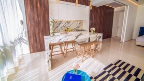 Una cocina moderna con encimera de mármol, taburetes de madera e iluminación colgante.