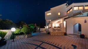Un edificio moderno con un cortile lastricato, un muro in pietra e un ingresso ben illuminato.
