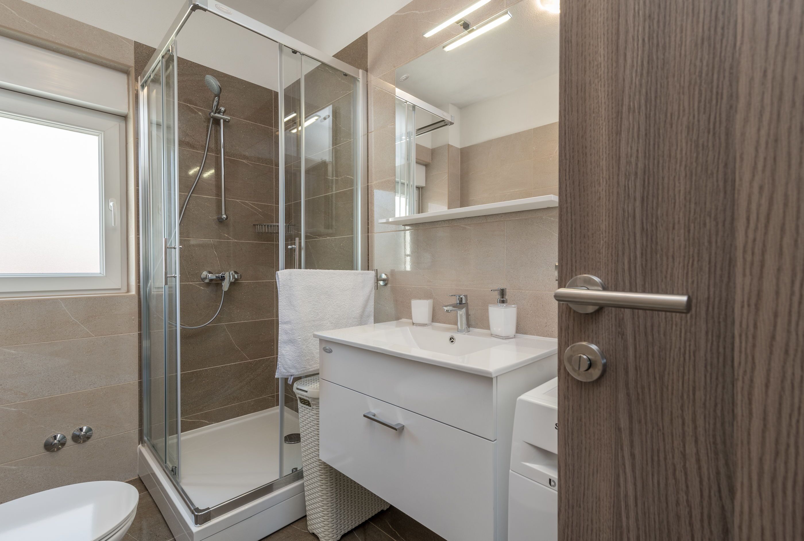 A modern bathroom with a glass-enclosed shower, a white sink, and a mirror above the vanity.