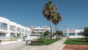 A modern building with a white facade, a paved walkway, and a bench. - Stylish apartment with amazing views of the Ria Formosa & the sea in Fuseta. (Fuseta, Moncarapacho.)