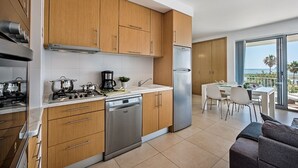 A modern kitchen with wooden cabinets, stainless steel appliances, and a dining area with a view of the ocean. - Stylish apartment with amazing views of the Ria Formosa & the sea in Fuseta. (Fuseta, Moncarapacho.)