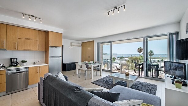 A modern apartment with a kitchen, dining area, and a balcony with a view of the ocean. - Stylish apartment with amazing views of the Ria Formosa & the sea in Fuseta. (Fuseta, Moncarapacho.)