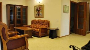 A living room with a patterned sofa, a wooden cabinet, and a small table. - Apartment on Ismayil bay Qurtqashinli 50 (Baku)