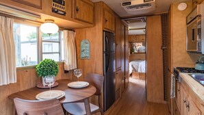 Una cocina compacta con armarios de madera, un refrigerador y un comedor con mesa y sillas.