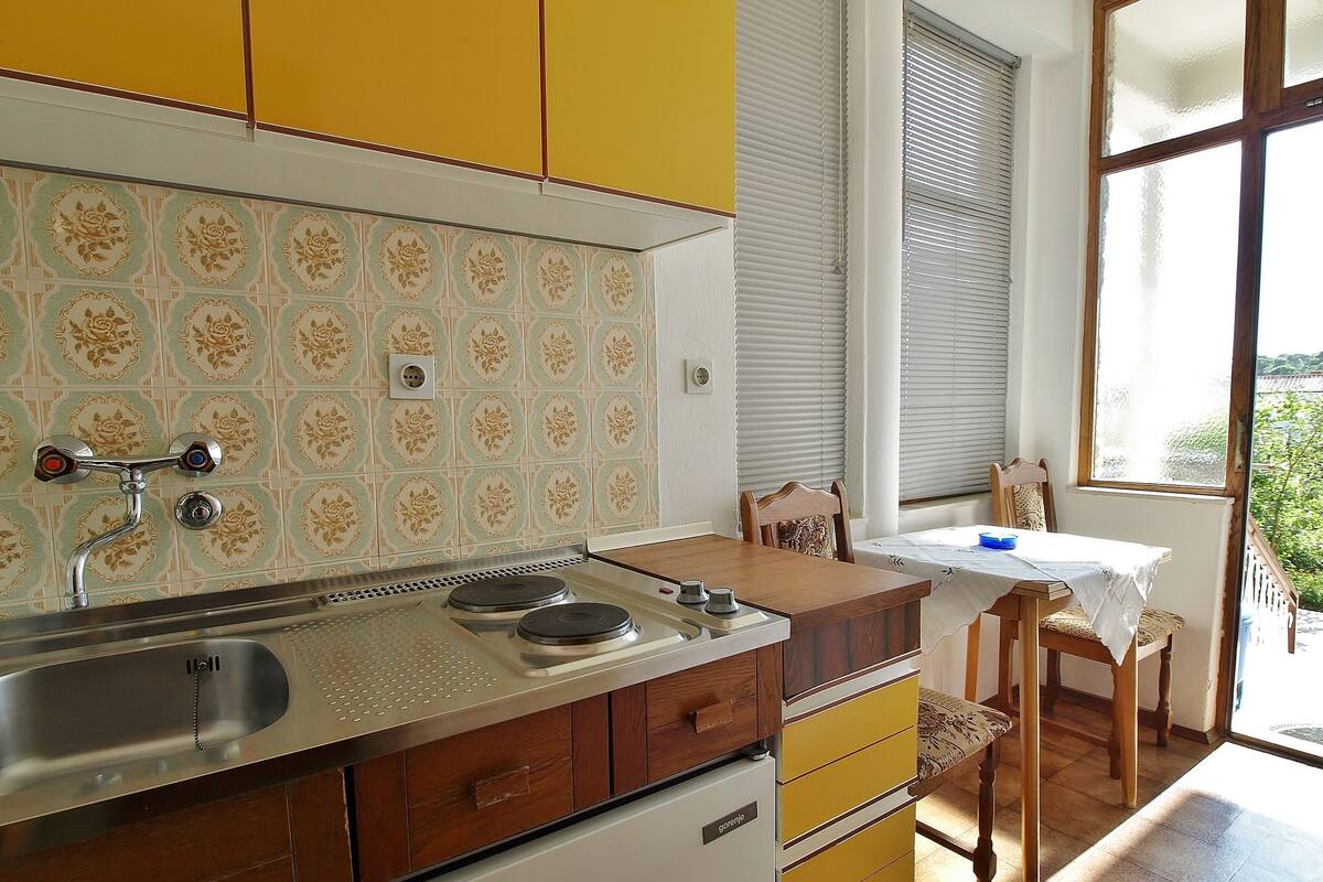 A kitchen with a sink, stove, and wooden cabinets.