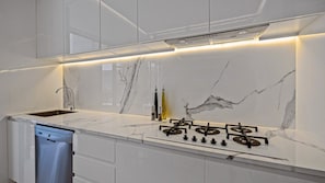 Eine moderne Küche mit eingebautem Geschirrspüler, einem Gasherd und einer Marmor-Spritzschutzwand.