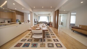 A modern kitchen with a dining area, wooden cabinets, and a patterned rug. - Onnason vacation rental K (Onna)