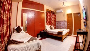 Quarto de hotel com duas camas, um guarda-roupa, uma televisão e uma pequena mesa.