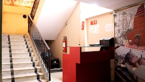 Uma escadaria com um balcão de recepção vermelho e um extintor de incêndio.
