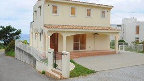 A two-story house with a tiled roof, a covered porch, and a fenced driveway. - Onnason vacation rental C (Onna)