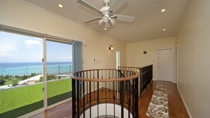 A spacious balcony with a view of the ocean, a ceiling fan, and a wooden staircase. - Onnason vacation rental C (Onna)