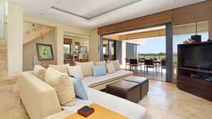 A modern living room with a sofa, ottomans, a coffee table, and a TV. - Vacation Villa 2WW (Cape Town)
