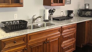 Una cocina con armarios de madera, encimera de granito, pileta y cafetera.