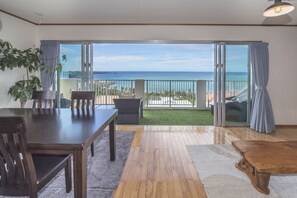 A spacious balcony with a view of the ocean, a dining area with a table and chairs, and a wooden coffee table. - Onnason vacation rental  J (Onna)