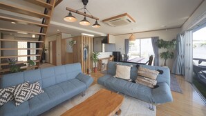 Un salon spacieux avec deux canapés bleus, une table basse en bois et un escalier menant à un autre niveau.