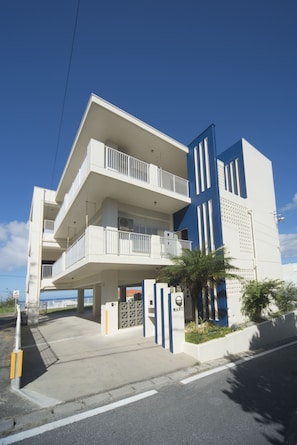 A multi-story building with balconies, a gated entrance, and a clear sky. - Onnason vacation rental  J (Onna)