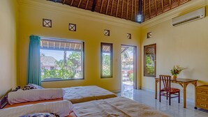 A hotel room with two beds, a desk, and a chair. There are windows with views of greenery and a building outside. - Villa Sari Cucukan (Gianyar)