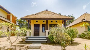 A bungalow with a thatched roof, a small porch, and a staircase leading to the entrance. - Villa Sari Cucukan (Gianyar)