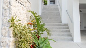 A modern building with a stone wall, a staircase, and a variety of plants. - Onnason vacation rental N (Onna)