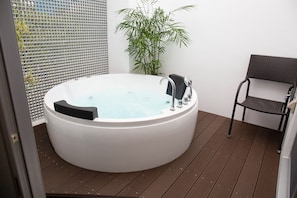 Un espace de détente avec un grand jacuzzi, un fauteuil et une plante en pot.