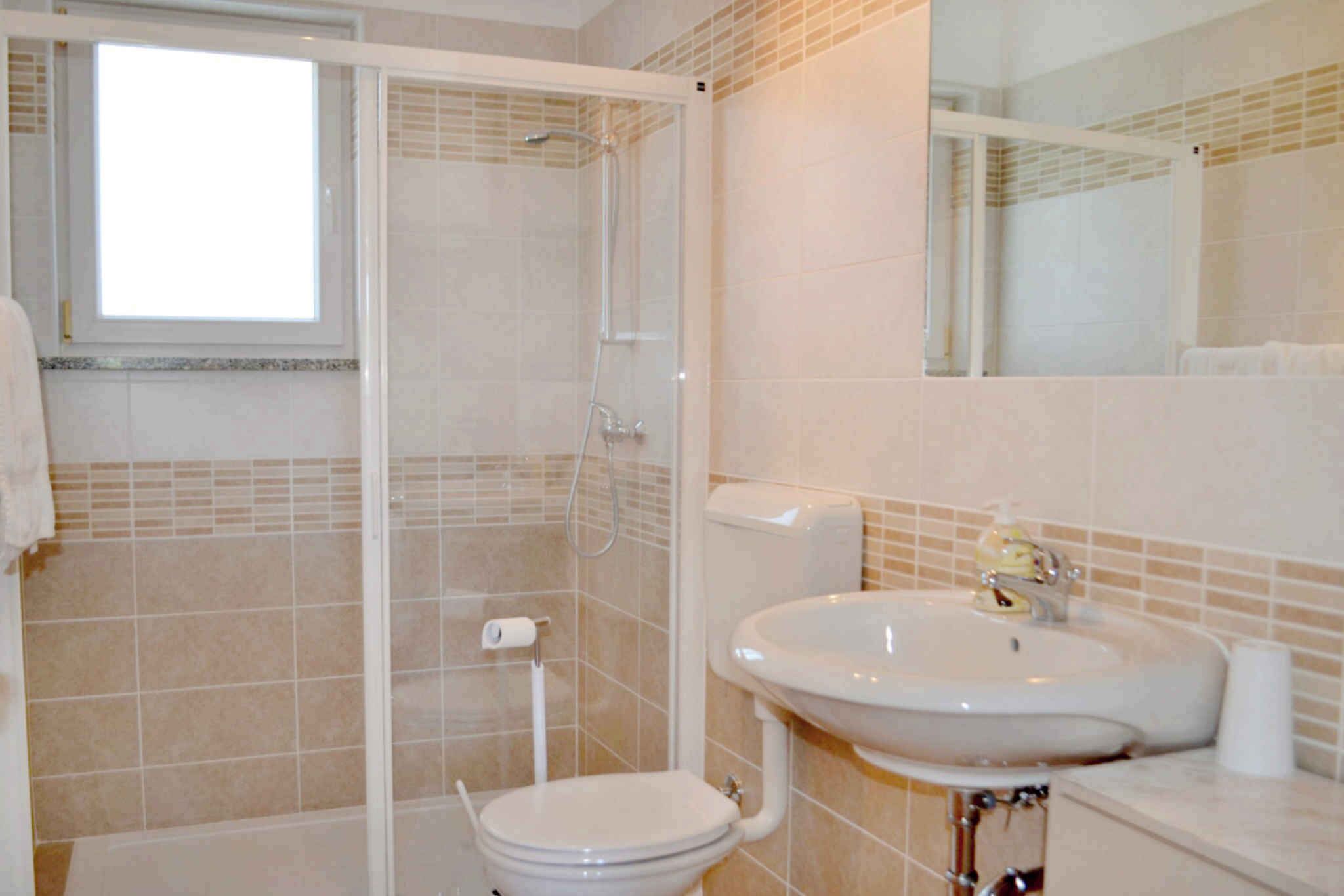 A bathroom with a shower, toilet, sink, and a mirror.
