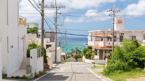 Une rue côtière bordée d’immeubles, de lignes électriques et offrant une vue dégagée sur l’océan.